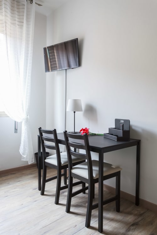 Modern writing desk with black chairs, flat screen TV, and lamp in Bologna apartment Il Filo di Arianna