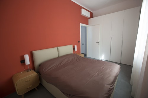 Camera moderna con parete color corallo, testiera crema, biancheria marrone e armadio bianco presso L'Appartamento Giusto a Bologna