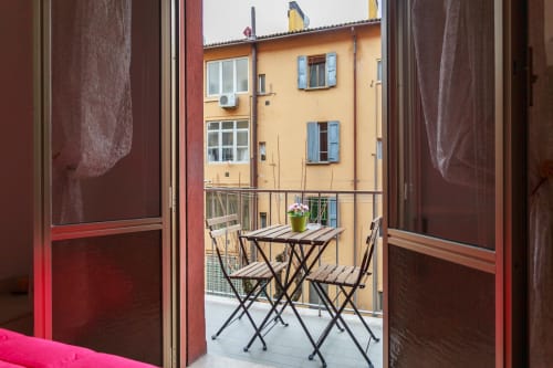 Balcony with table and chairs overlooking yellow building in Bologna at L'Appartamento Giusto