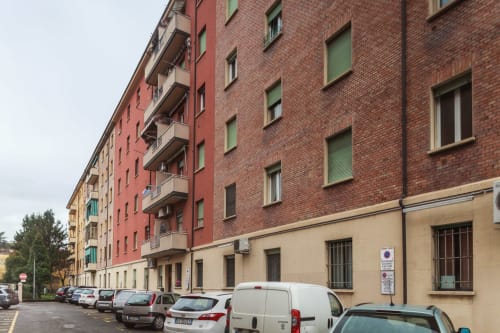 L'Appartamento Giusto BnB exterior in Bologna showing colorful residential building with parked cars and balconies