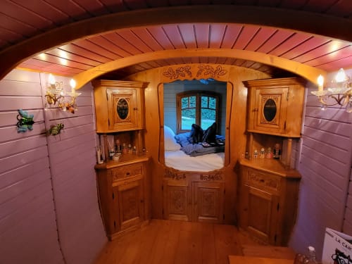 Intérieur cosy du chalet Les Refuges avec meubles sculptés, éclairage tamisé et vue sur la chambre