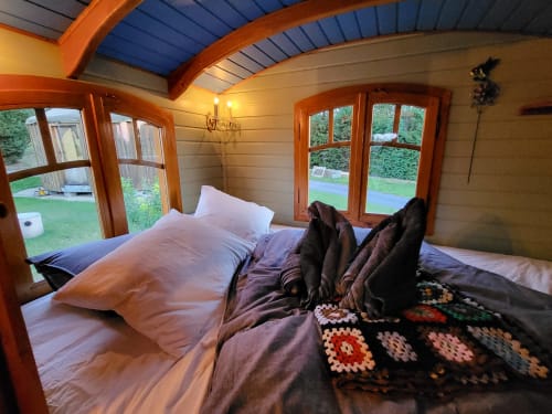 Chambre cosy de la cottage La Roulotte des Oiseaux aux Refuges Du Chalet, Jalhay avec poutres en bois et vue sur le jardin