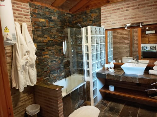 Lujoso baño en la Casita Estrella de las Nieves de El Paraje del Chef, Granada, con paredes de ladrillo rústico y ducha de cristal,