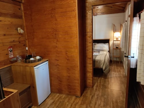 Acogedor interior de cabaña de madera en El Paraje del Chef con cocina, minibar blanco y vista del dormitorio en Laroles Nevada