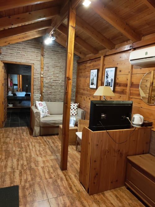Interior de cabaña rústica en El Paraje del Chef con televisor, cómodos asientos y vigas de madera vista en Laroles Nevada, Granada