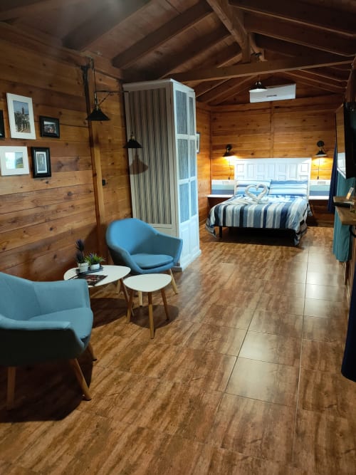 Cabaña Gencianilla en El Paraje del Chef, Granada con interior de madera, butacas azules y cama queen con dosel