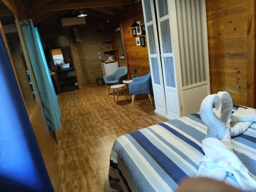Dormitorio Gencianilla en El Paraje del Chef con ropa de cama rayada, sillones azules, paredes de madera y comodidades modernas