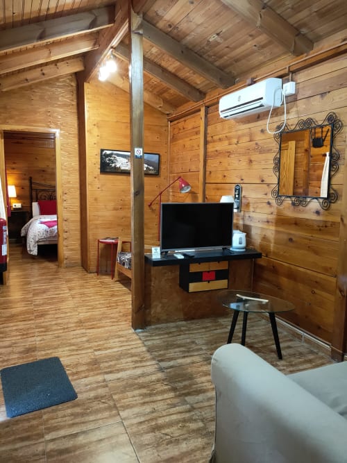 Interior acogedor de cabaña de madera en El Paraje del Chef con TV, decorado con vistas a la montaña y comodidades modernas en Laroles