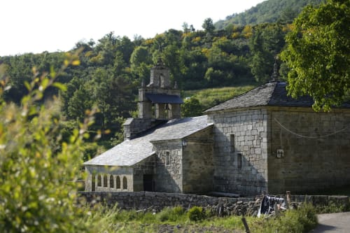 Capilla rural de piedra rodeada de verdes colinas junto a Prado Novo, León, España