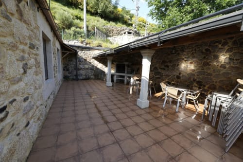 Patio cubierto con baldosas de barro y columnas blancas en Vivienda Balbino, Suárbol, León