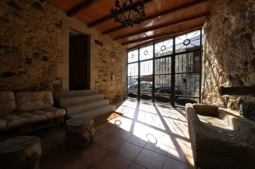 Interior de piedra con vigas de madera, terraza soleada y mobiliario rústico en la casa vacacional Balbino, León, España