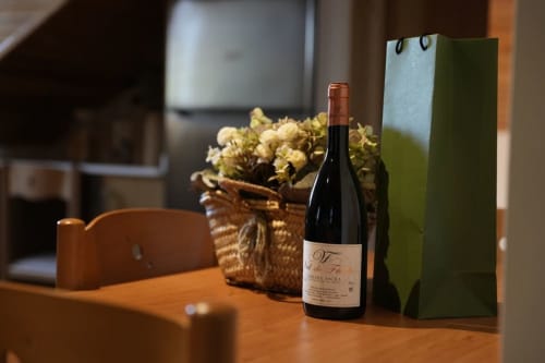 Botella de vino y flores secas sobre mesa de madera en Vivienda de uso turístico Balbino, León