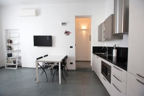 Moderno appartamento open-plan a L'Appartamento Giusto a Bologna con cucina, zona pranzo, soggiorno, TV e ripiani bianchi.