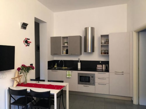 Cucina e zona pranzo moderna all'Appartamento Giusto a Bologna con mobili bianchi, piani neri e tavolo con posti a sedere