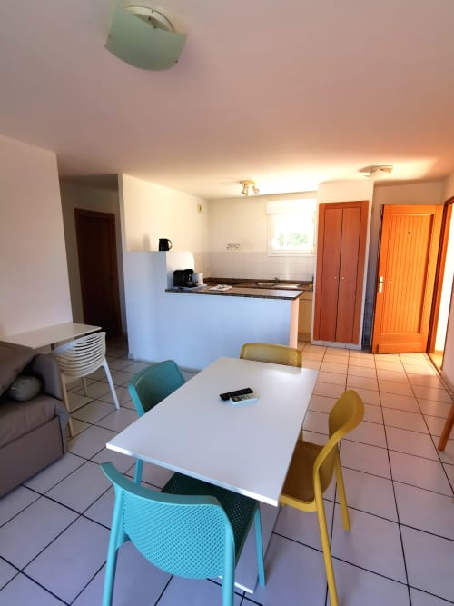 Appartement Résidence Saint Michel à L'île Rousse avec table à manger, chaises colorées et cuisine ouverte