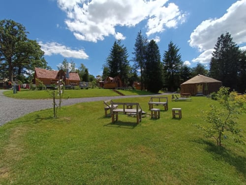 Buiten picknickgebied van Les Refuges Du Chalet met houten tafels en lodge-gebouwen in Jalhay, België