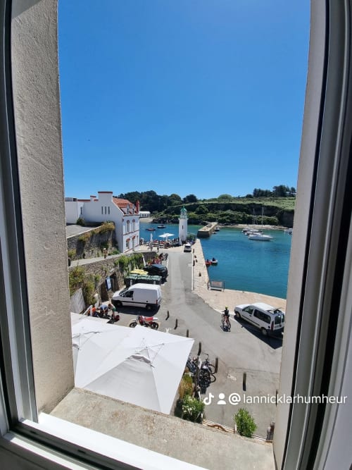 Vue côtière depuis l'appartement Loc'Maria à Belle Île-en-Mer, France avec port turquoise et phare blanc