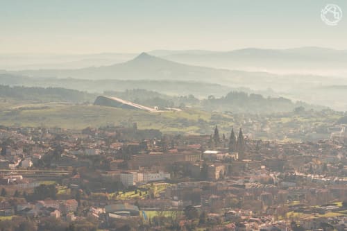 Vista aérea de Santiago de Compostela con las agujas de la catedral, la ciudad circundante, montañas y un paisaje de valle brumoso