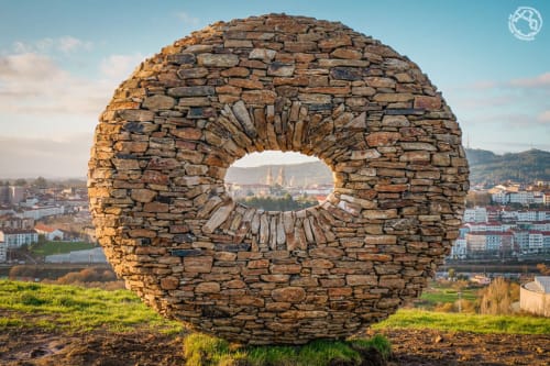 Escultura de piedra con abertura circular que domina la catedral de Santiago de Compostela y el paisaje urbano