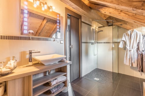 Luxurious bathroom in Mont-Blanc Suite at Les Edelweiss, Passy, featuring wooden beams, vessel sink, walk-in shower, and