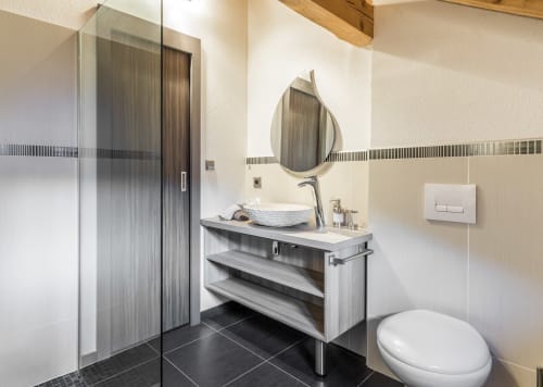Modern bathroom in Les Edelweiss Mont-Blanc suite with vessel sink, teardrop mirror, and black tile flooring