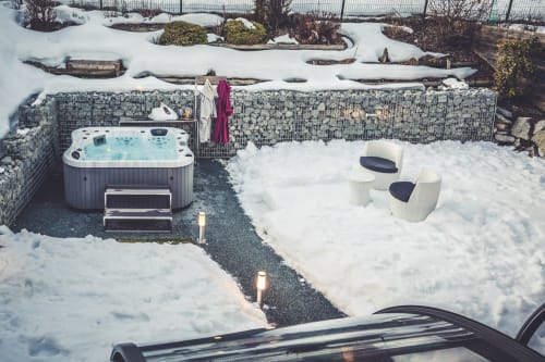 Snowy hot tub and seating area at Les Edelweiss Mont-Blanc in Passy, with mountain views and heated water in winter