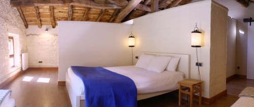 Dormitorio espacioso en Casa rural MAÑARINEGI con manta azul, luces colgantes, vigas de madera y paredes de piedra rústica