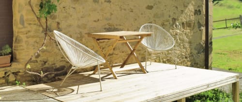 Patio de piedra rústico de Casa rural MAÑARINEGI con sillas tejidas blancas, mesa de madera y vistas al jardín en Gipuzkoa