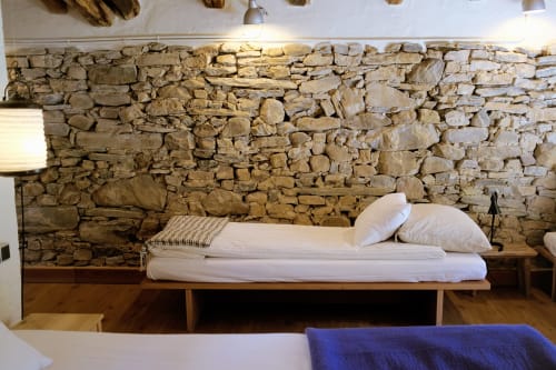 Pared de piedra rústica detrás de cama de madera minimalista con ropa de cama blanca en Casa rural MAÑARINEGI Landa apartamentuak