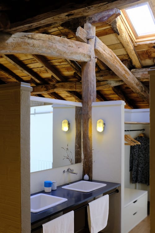 Baño moderno con encimera negra bajo vigas de madera vista en Casa rural MAÑARINEGI en Gipuzkoa