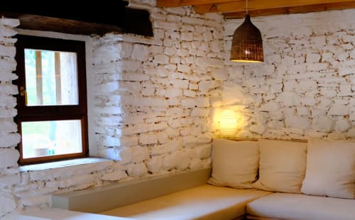 Acogedor dormitorio con paredes de ladrillo blanco en Casa rural Mañarinegi, cama, ventana, lámpara colgante y almohadas color crema en Gipuzkoa