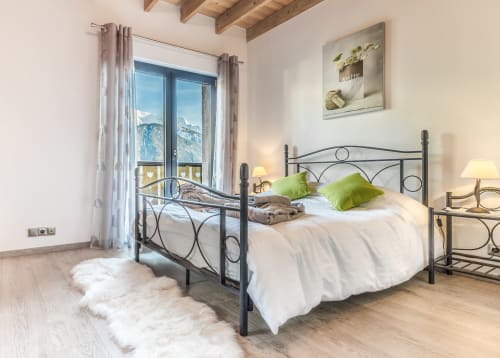 Bright bedroom at Les Edelweiss Mont-Blanc in Passy with wrought iron bed, green pillows, and mountain views