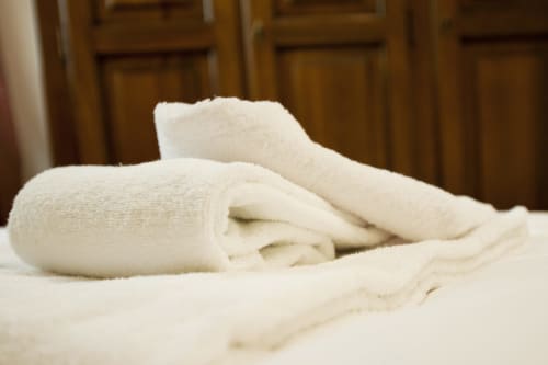 Asciugamani bianchi ordinatamente arrotolati sul letto della Residence La Corte, un bed and breakfast a Vezza d'Oglio, Italia