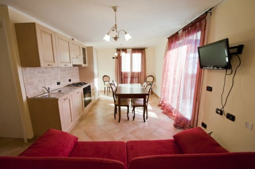 Cucina e zona living a pianta aperta in appartamento con 1 camera presso Residence La Corte, Vezza d'Oglio, con tavolo da pranzo rosso