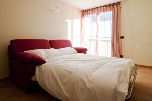 Moderno divano letto estraibile in velluto bordeaux con biancheria bianca in luminoso appartamento presso Residence La Corte, Vezza d'Oglio