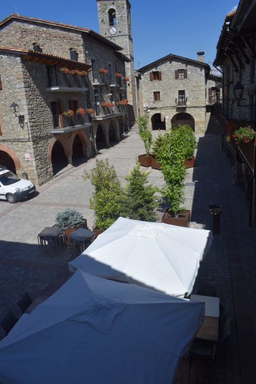 Plaza medieval de piedra en el hostal La Calma De Bellver en Bellver de la Cerdanya con torre del reloj