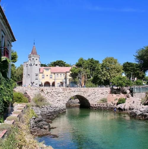 Castelo medieval com torre dominando águas turquesas e ponte de pedra em Leiria, destino cheio de charme