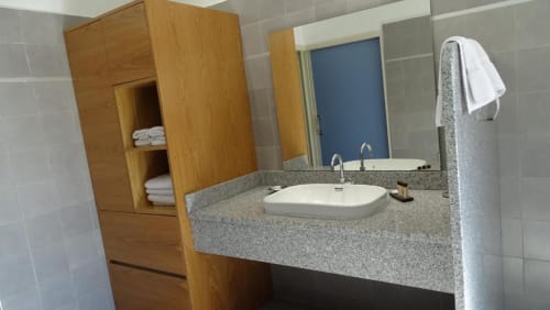 Salle de bains moderne à la Résidence Saint Michel avec double vasque, plan de travail en granit gris, meuble de rangement en bois et serviettes blanches