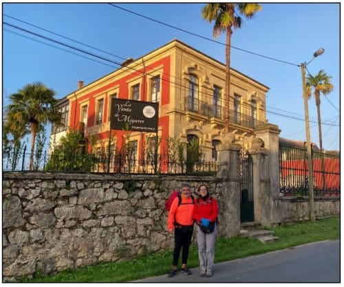 Hotel La Venta de Miyares en Asturias con fachada colonial roja y amarilla, huéspedes posando frente a muros de piedra