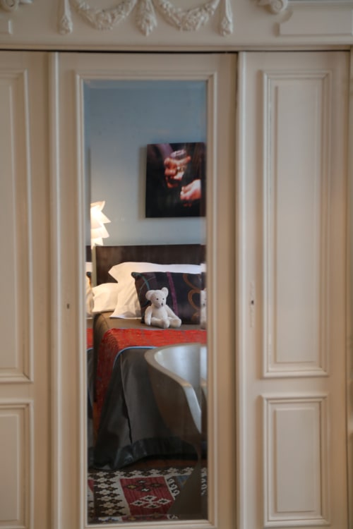 Chambre du Gîte Le Grand Duc à Valenciennes avec lit, peluche et décoration murale visible par l'embrasure de la porte