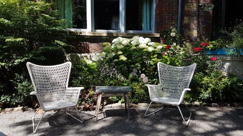 Deux chaises en rotin blanc avec petite table dans le jardin luxuriant du Gîte Le Grand Duc, Valenciennes