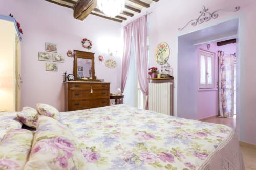 Affascinante camera da letto lavanda a Dormire Assisi B&B con biancheria floreale, cassettone in legno e vista sul giardino