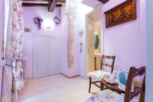 Camera rosa al Dormire Assisi B&B con decorazioni floreali, travi in legno e accesso al bagno