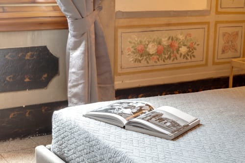 Camera da letto di lusso presso Sleep tight Florence con riviste aperte sul letto, mobili in legno classico con intarsi floreali,