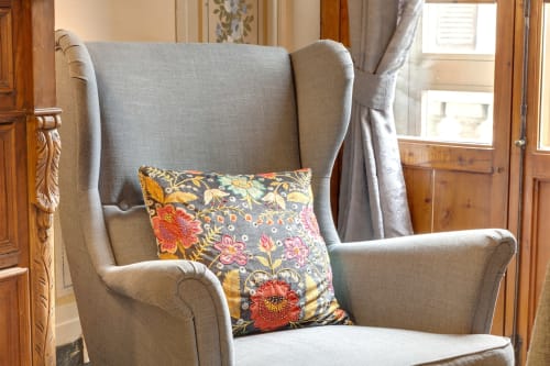 Poltrona grigia in stile wingback con cuscino floreale colorato nell'appartamento di lusso Sleep tight Florence, Firenze