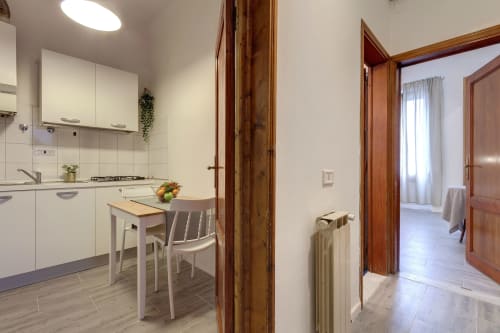 Modern kitchen-dining area in Sleep tight Florence Superior Apartment with white cabinetry, wooden beams, and dining table