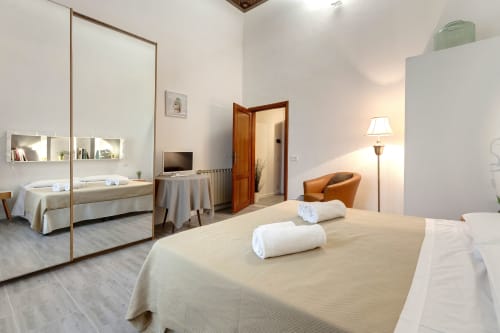 Superior apartment bedroom at Sleep tight Florence B&B in Firenze, featuring bed with rolled towels, mirror, TV, and cognac