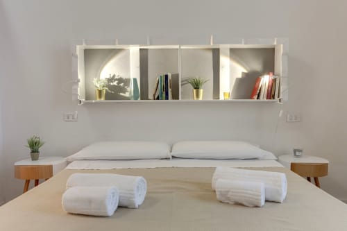 Modern bedroom at Sleep tight Florence BnB with white shelving, pillows, rolled towels, and wooden bedside tables in Florence