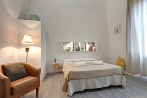 Superior apartment at Sleep tight Florence with brown leather armchair, bed with white bedding, wall shelving, and warm