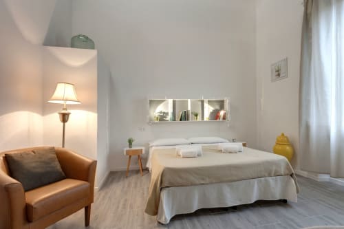 Modern bedroom in Sleep tight Florence BnB with queen bed, leather armchair, wall shelving, and ambient lighting in Firenze